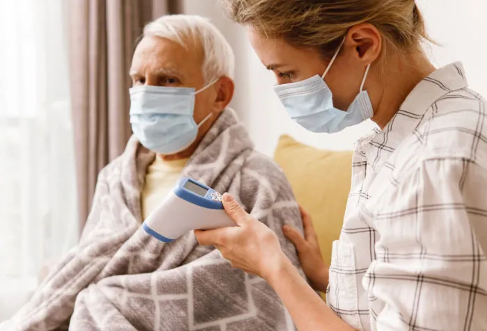 a couple of people sitting on a couch wearing face masks