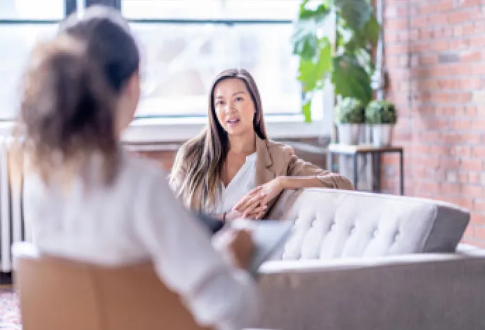 a woman sitting on a couch talking to another woman