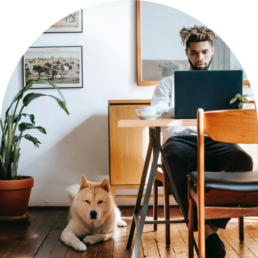 a man sitting at a desk with a laptop and a dog